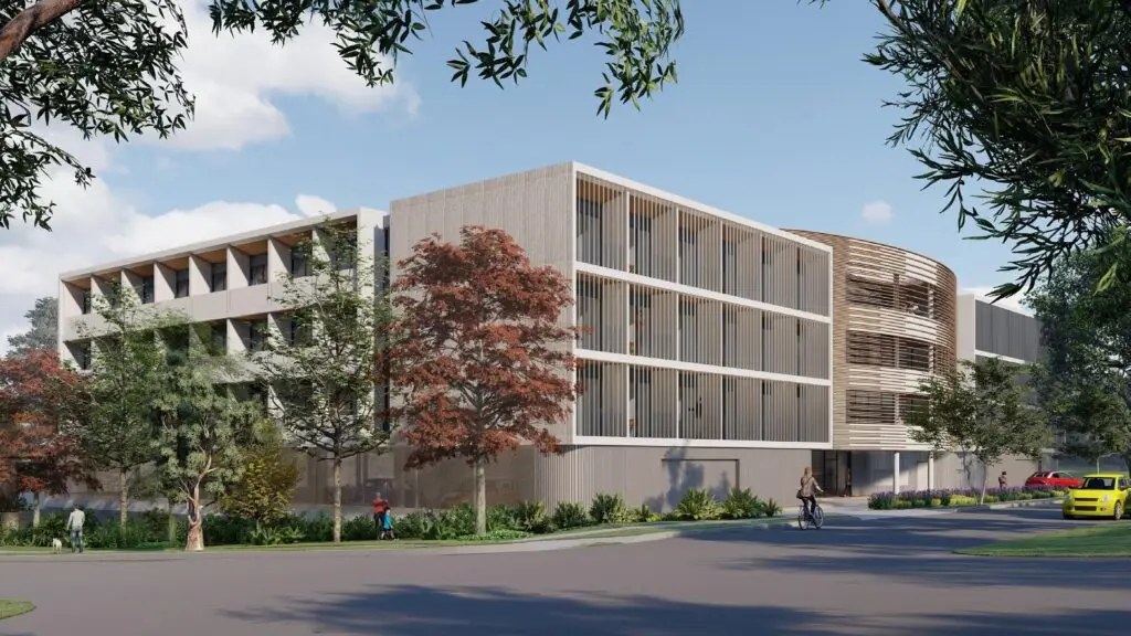 A digital rendering of a four-storey modern co-living housing development surrounded by trees, with pedestrians and cyclists in the foreground. The building features a contemporary design with vertical louvers and a mix of materials.