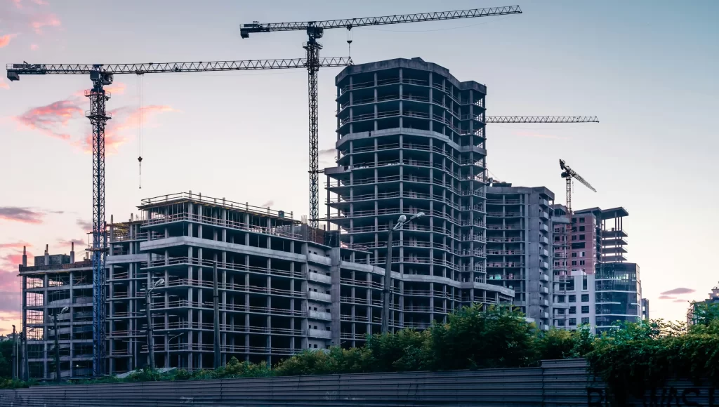 High-rise buildings under construction with cranes at sunset, representing urban development and infrastructure growth.