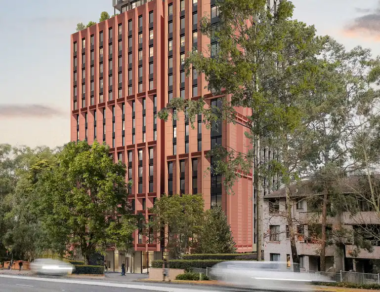 19-storey student accommodation building with a modern red-brick and glass facade, surrounded by trees and set against a clear sky.