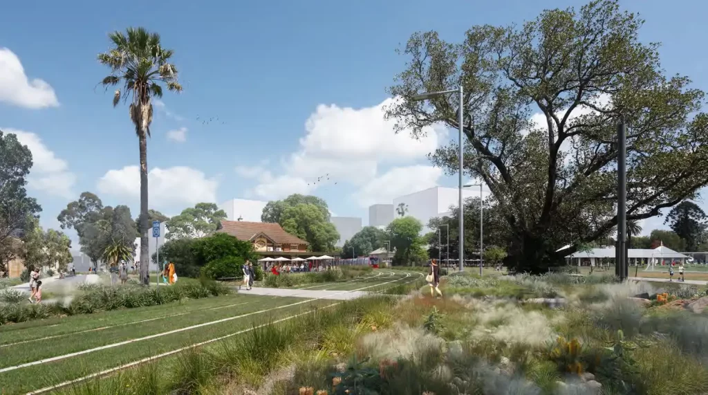 Artist's impression of the Parramatta North Precinct, featuring landscaped greenery, a walking path, a historic building, and people enjoying the open space under clear blue skies.