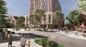 A modern architectural rendering of a proposed 10-storey private hospital in Camperdown, Sydney. The image showcases a landscaped public plaza with trees, pedestrians, cyclists, and outdoor seating. The hospital features a contemporary facade with glass and warm-toned vertical panels. In the background, St John’s College and other heritage buildings contrast with the new development.