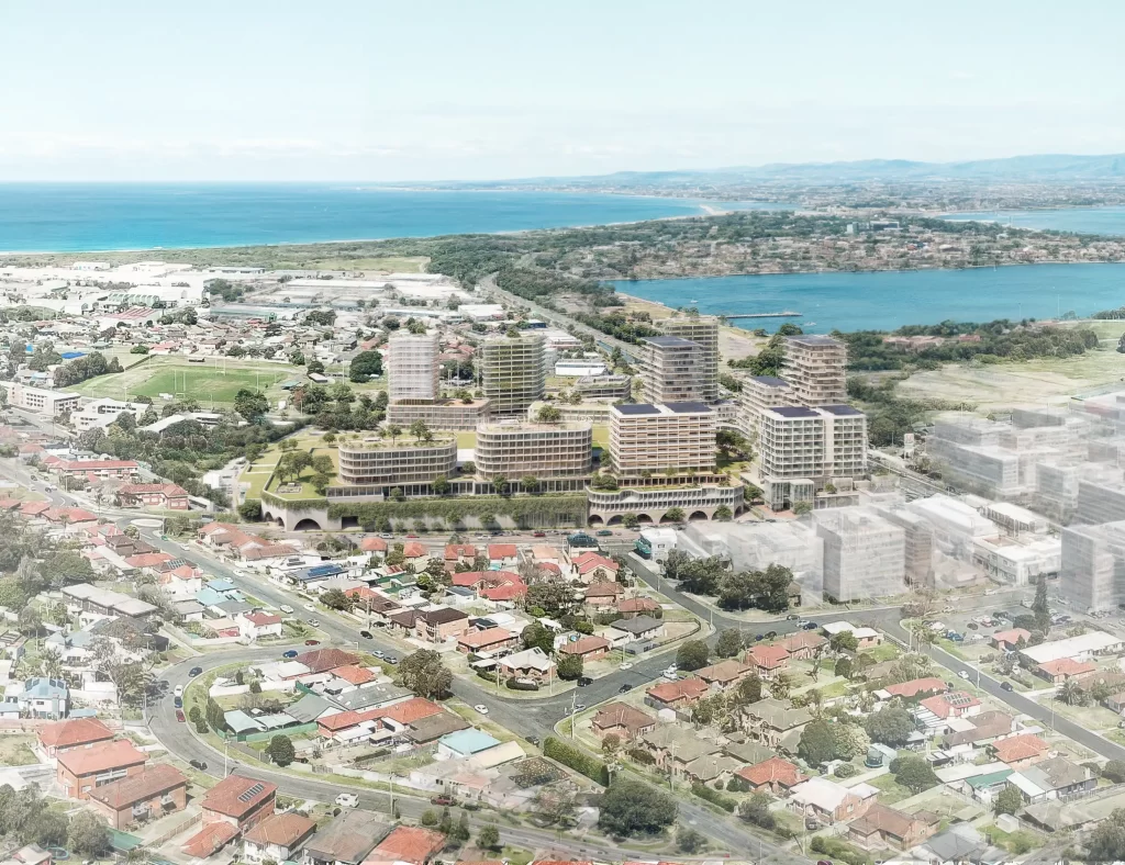 Aerial view of a proposed mixed-use development at Warrawong Plaza in Wollongong, featuring modern high-rise residential and commercial buildings with green rooftops. The development is set against the coastal landscape, with Lake Illawarra and the ocean visible in the background.