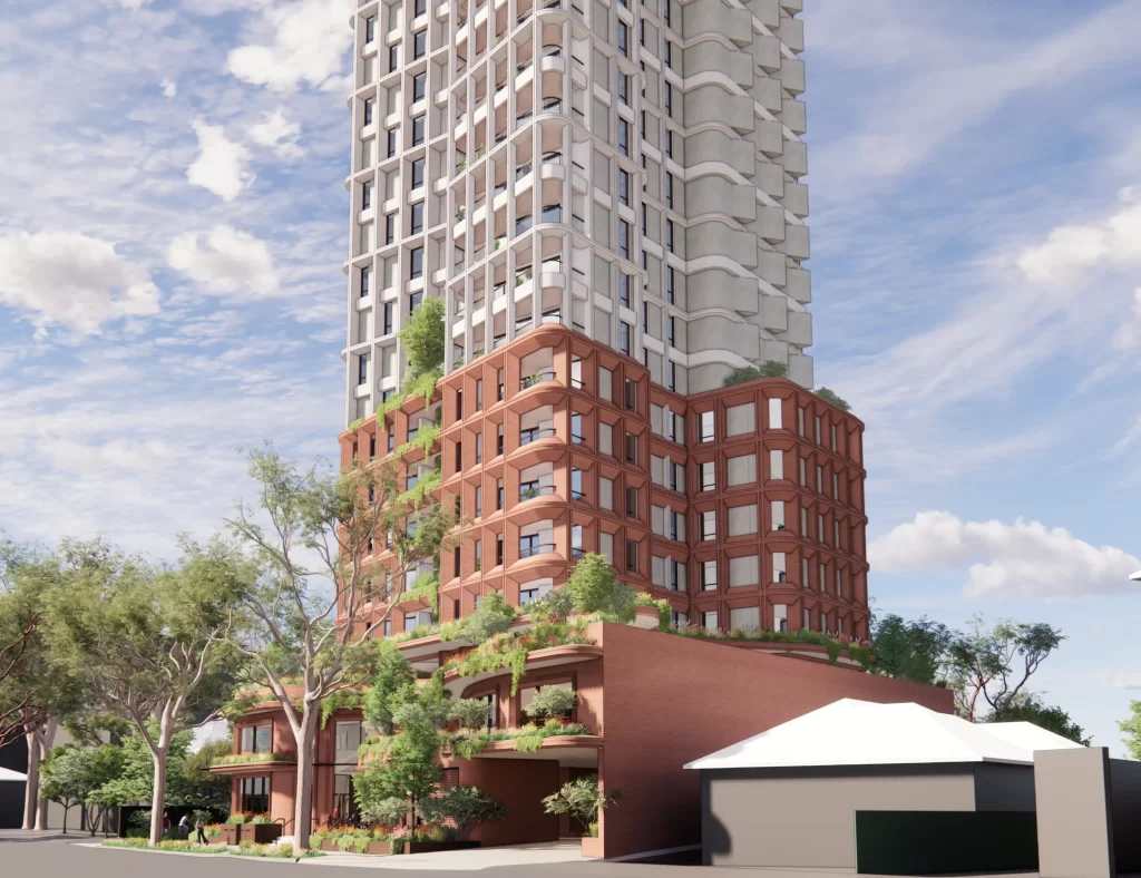 A 26-storey mixed-use residential tower with a red brick podium and green landscaping cascading down its lower levels. The upper floors feature a modern high-rise design with a textured white facade and curved balconies. The building is set within a tree-lined urban environment under a partly cloudy sky.