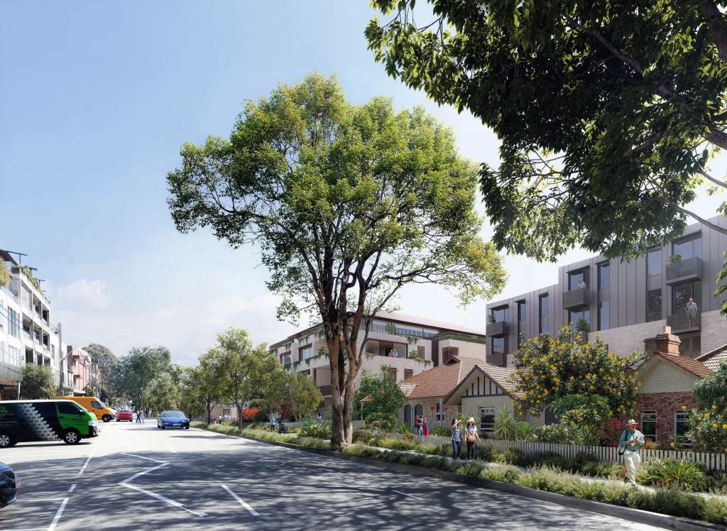 A streetscape view of the proposed Pathways Cremorne Seniors Housing development, featuring heritage cottages with preserved façades integrated alongside modern low-rise residential buildings. The tree-lined street includes parked cars and pedestrians, creating a community-oriented atmosphere.