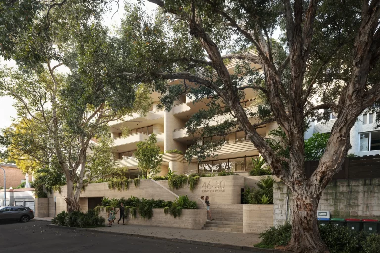 A modern five-storey residential building at 46-50 Lamrock Avenue, Bondi Beach, featuring curved balconies, lush landscaping, and a concrete façade. Large trees frame the view, and pedestrians walk along the footpath.