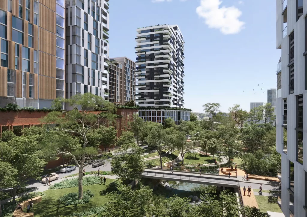 Rendering of high-rise residential towers surrounded by trees, pathways, and a landscaped public park with a pedestrian bridge.