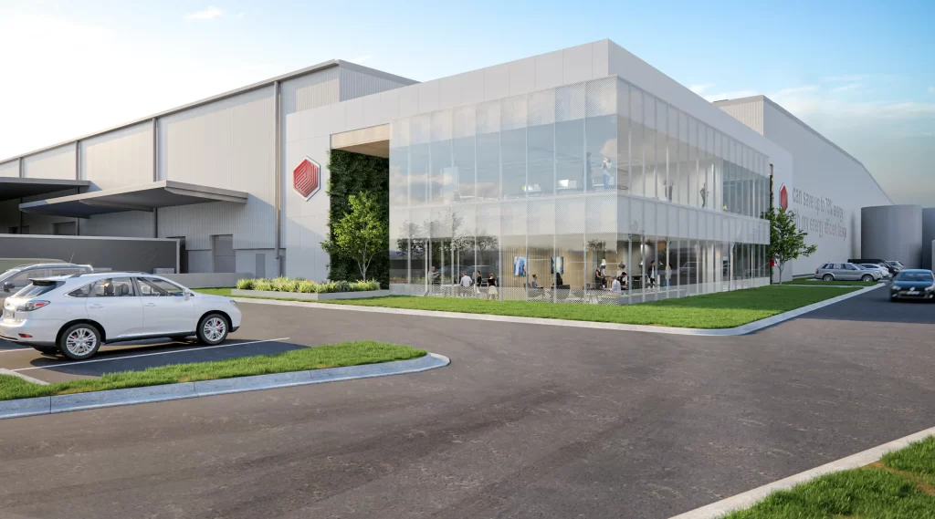 Modern warehouse and logistics facility with glass-fronted office, landscaped surrounds, and parked vehicles in foreground.