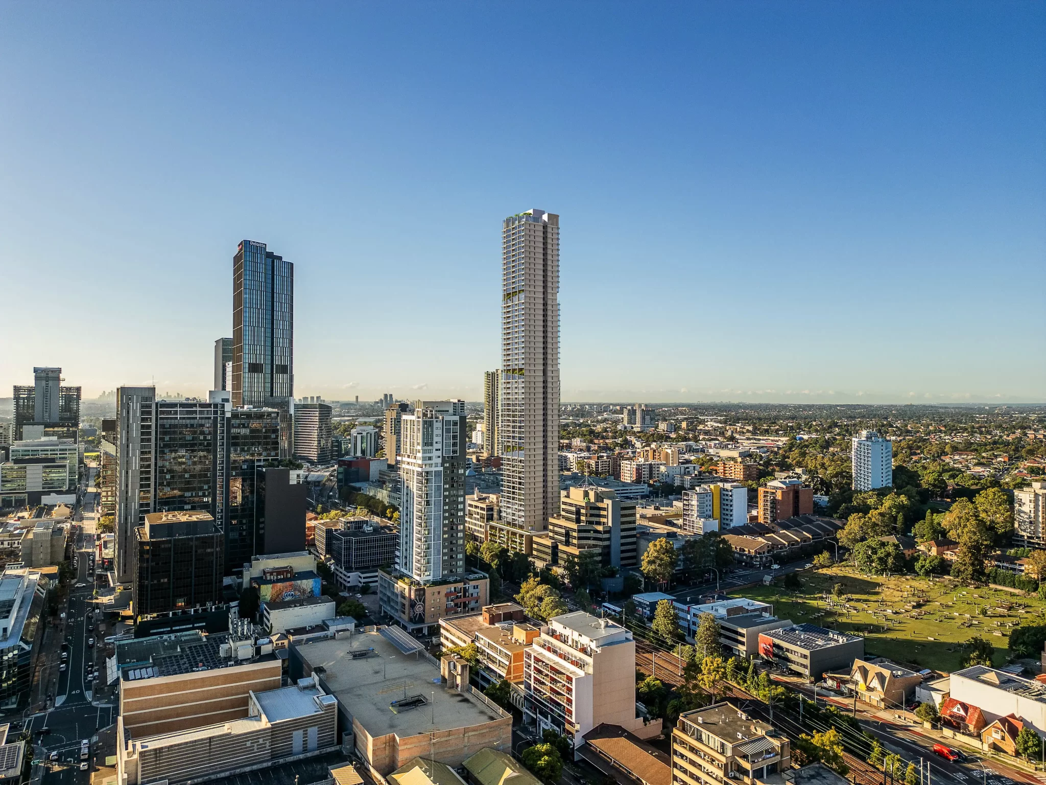 Aerial view of high-rise buildings and urban development in Parramatta, Sydney, with a clear blue sky in the background.