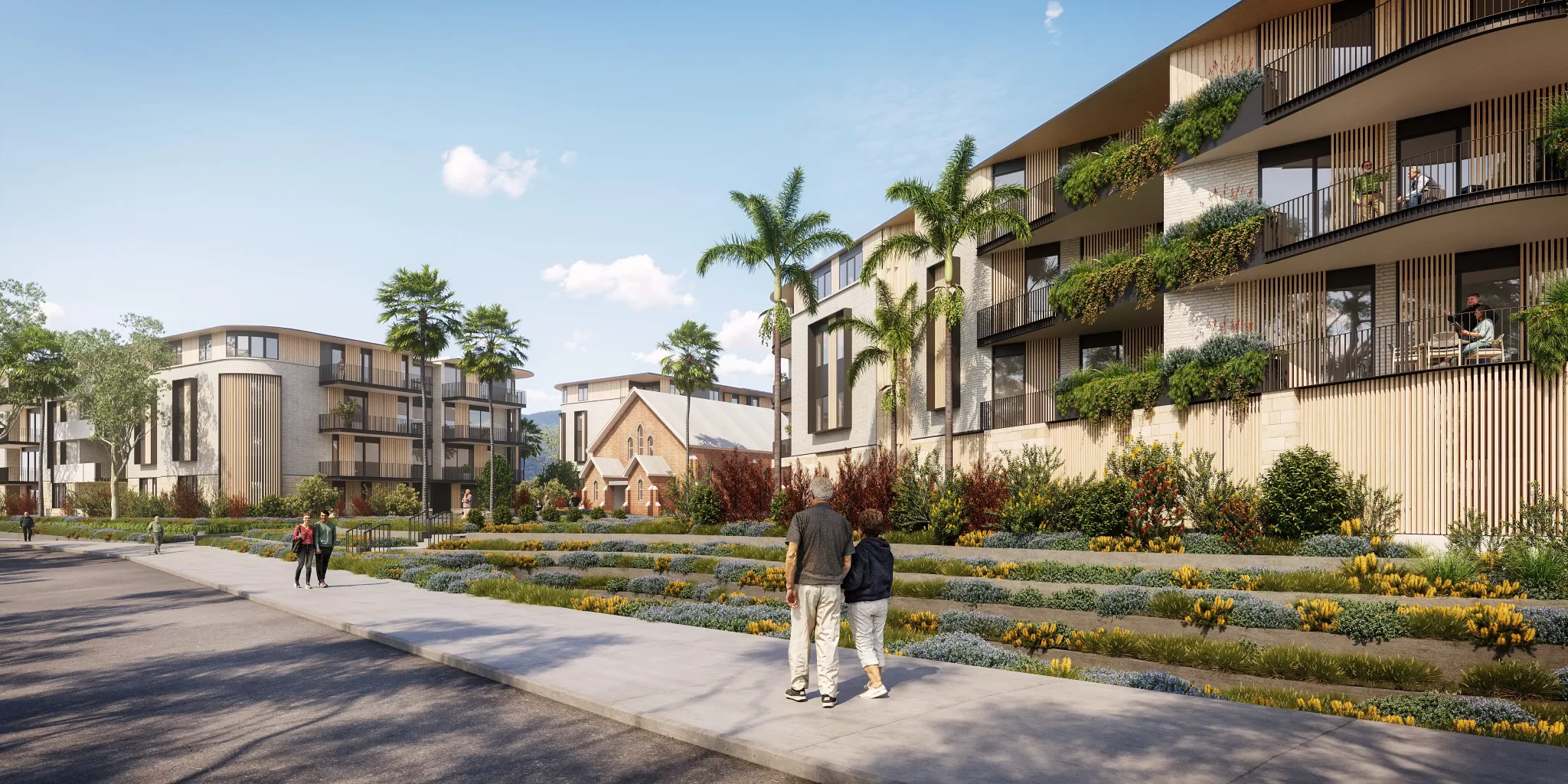 Street-level view of a modern seniors housing development with tiered landscaping, palm trees, and a heritage brick church in the centre.