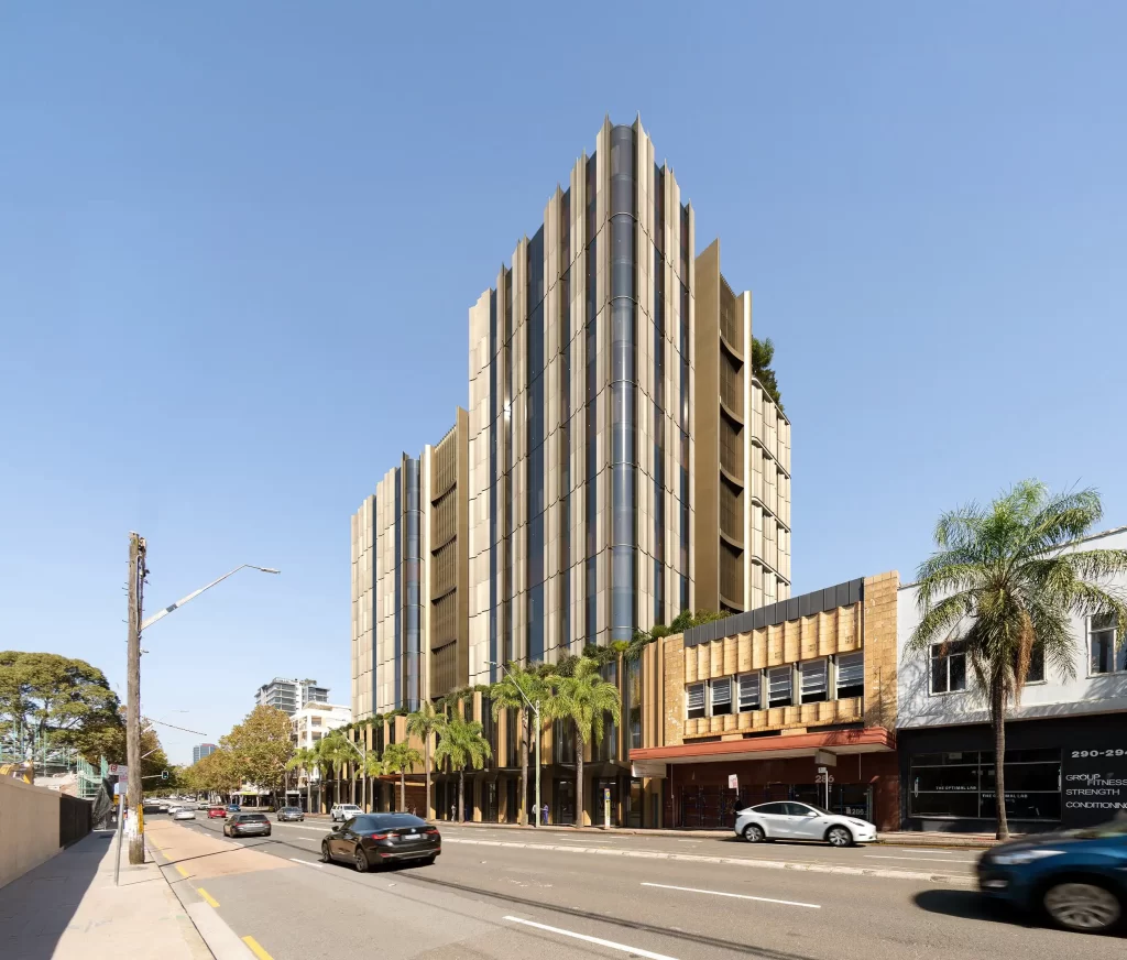 Street-level view of a proposed 16-storey mixed-use building at 270 Pacific Highway, Crows Nest, featuring a bronze-toned façade, vertical fins, and landscaped podium, with cars and palm trees along the footpath.